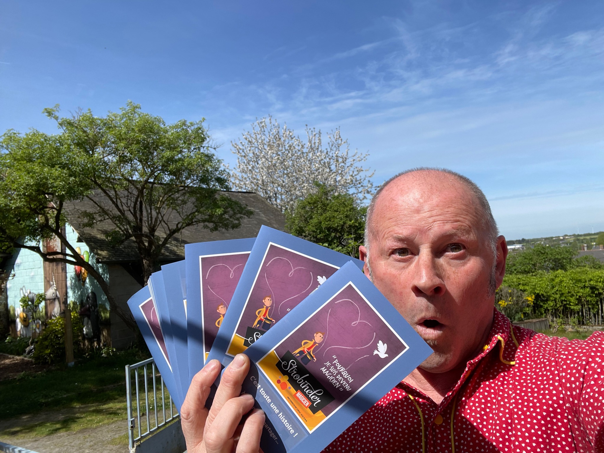 Strobineler présentant plusieurs livrets du spectacle dans un jardin