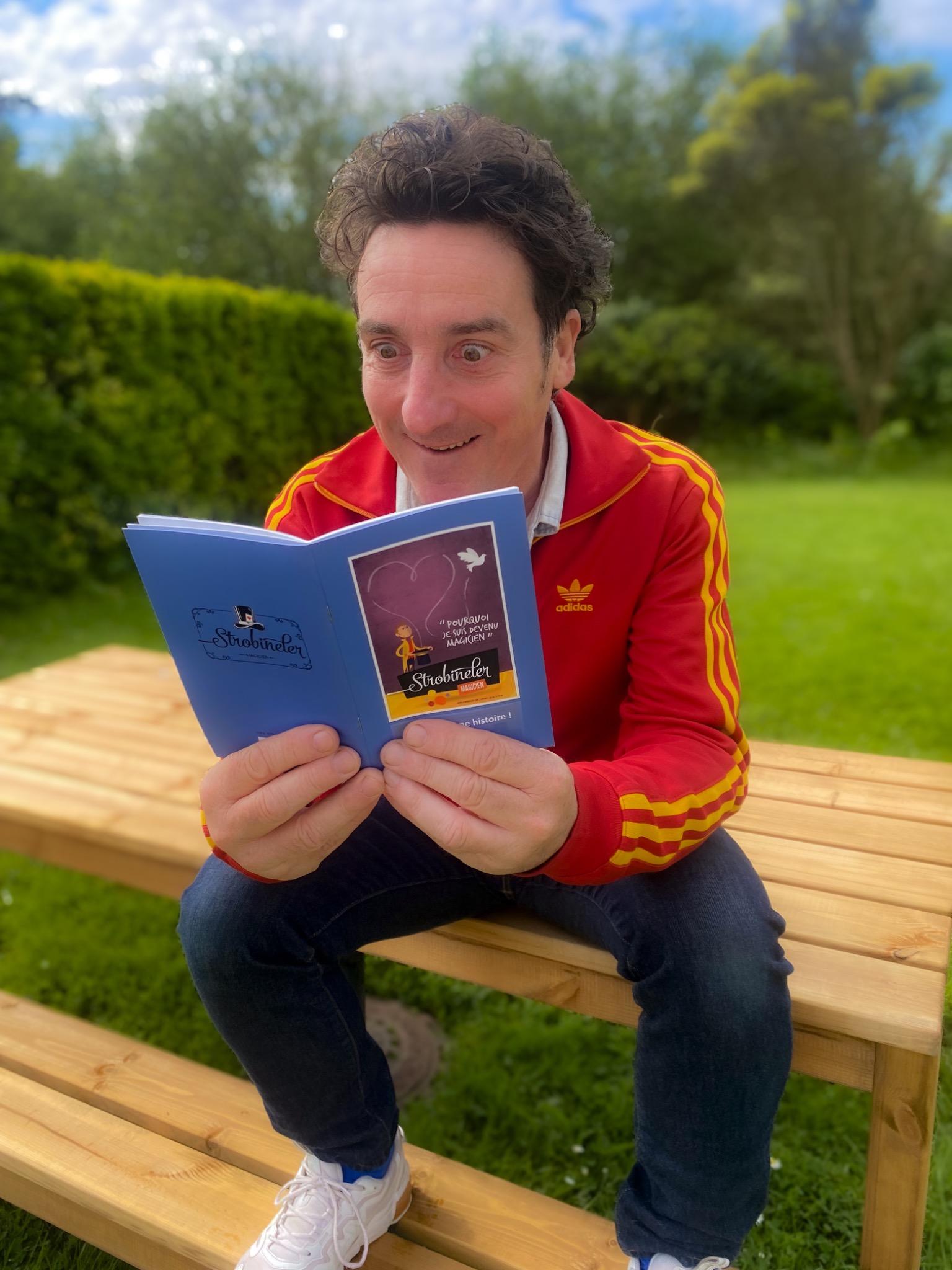 Un lecteur découvrant le livret du spectacle dans un jardin